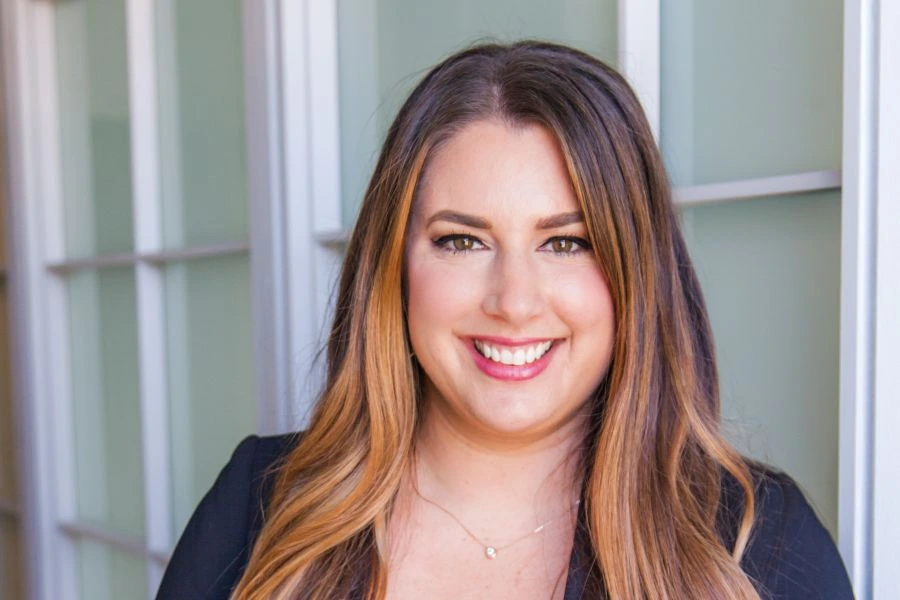 young woman in blue blazer smiling with windows in background
